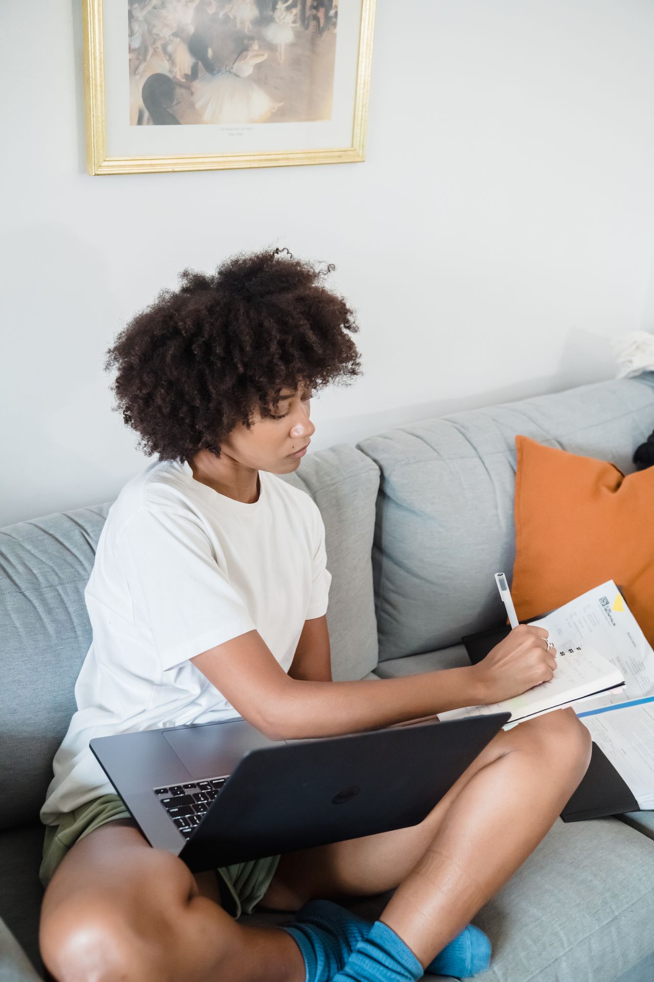 A student studying at home with a notebook and laptop